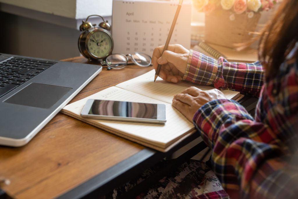 Calendar reminder event concept.Woman hand planner or organizer writing on diary book and 2020 Calendar page.Student planning appointment,noted and count Down schedule day