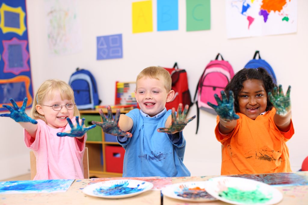 Three preschool kids with hands covered in paint