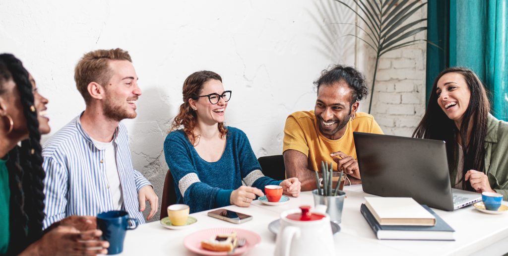 Group of students from different parts of the world having a brunch and studying in a cafeteria, young people having fun during a break in the morning