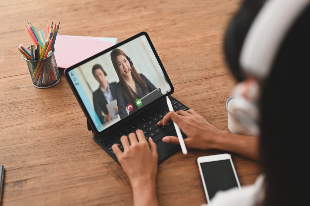 Cropped image woman is making a video call with her colleague while sitting in front of a computer tablet.