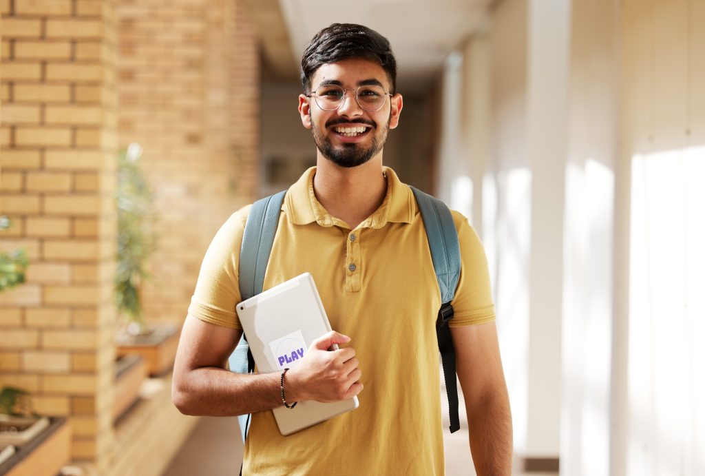 Face portrait, student and man in university ready for back to school learning, goals or targets. Scholarship, education and happy, confident and proud male from India holding tablet for studying.