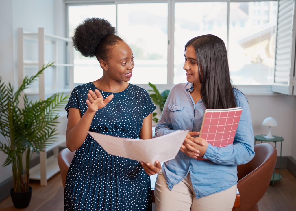 Two women discuss work solutions in boardroom office, mentorship learning. High quality photo