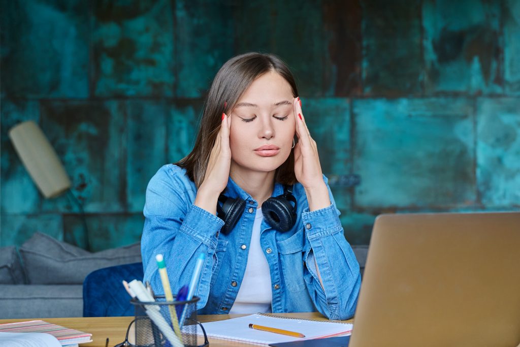 Unhappy sad female university student at home at her desk. Face of 20s young woman, stressed difficult situation, problems in studies