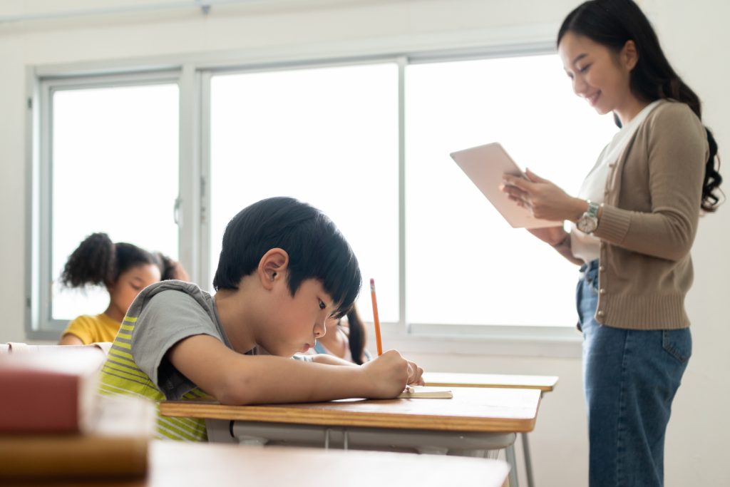 Asian children and Female teacher in classroom at elementary school. Examination, Learning and Education.