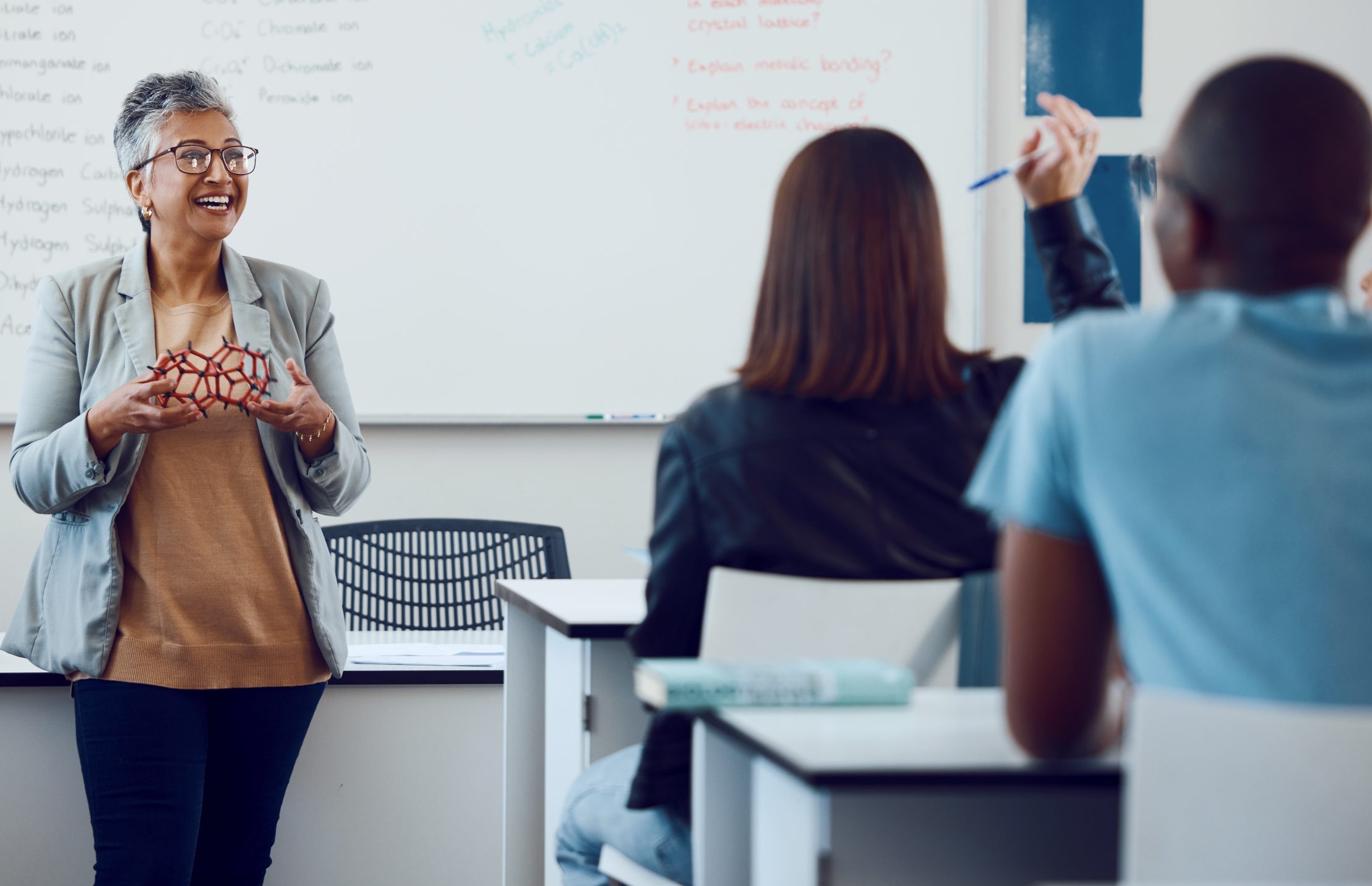 Physics, teaching and teacher in a class with students, studying molecules and communication in classroom at school. Chemistry, learning and woman with children for education on an atom at college