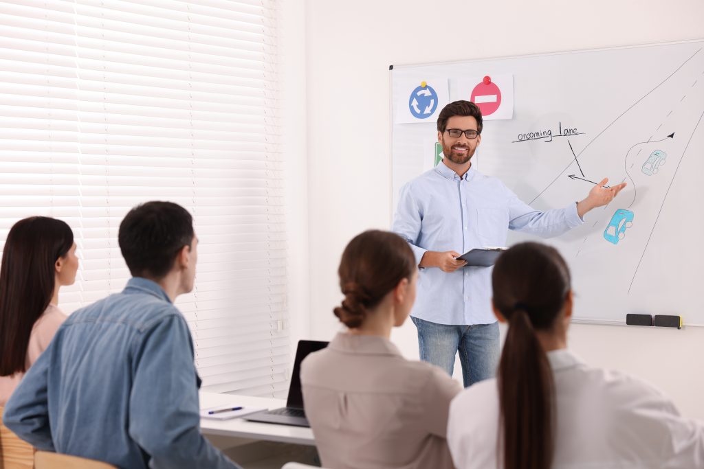 Teacher explaining traffic rules to audience during lesson in driving school