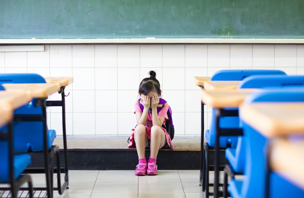 stress girl sitting and thinking on the classroom floor