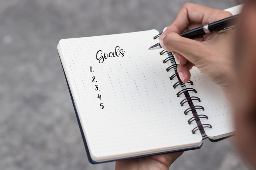 woman writing golds in a notebook.