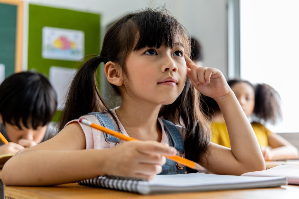 Portrait of an Asian child girl student thinking and solving the subject matter studied in the classroom. School education concept