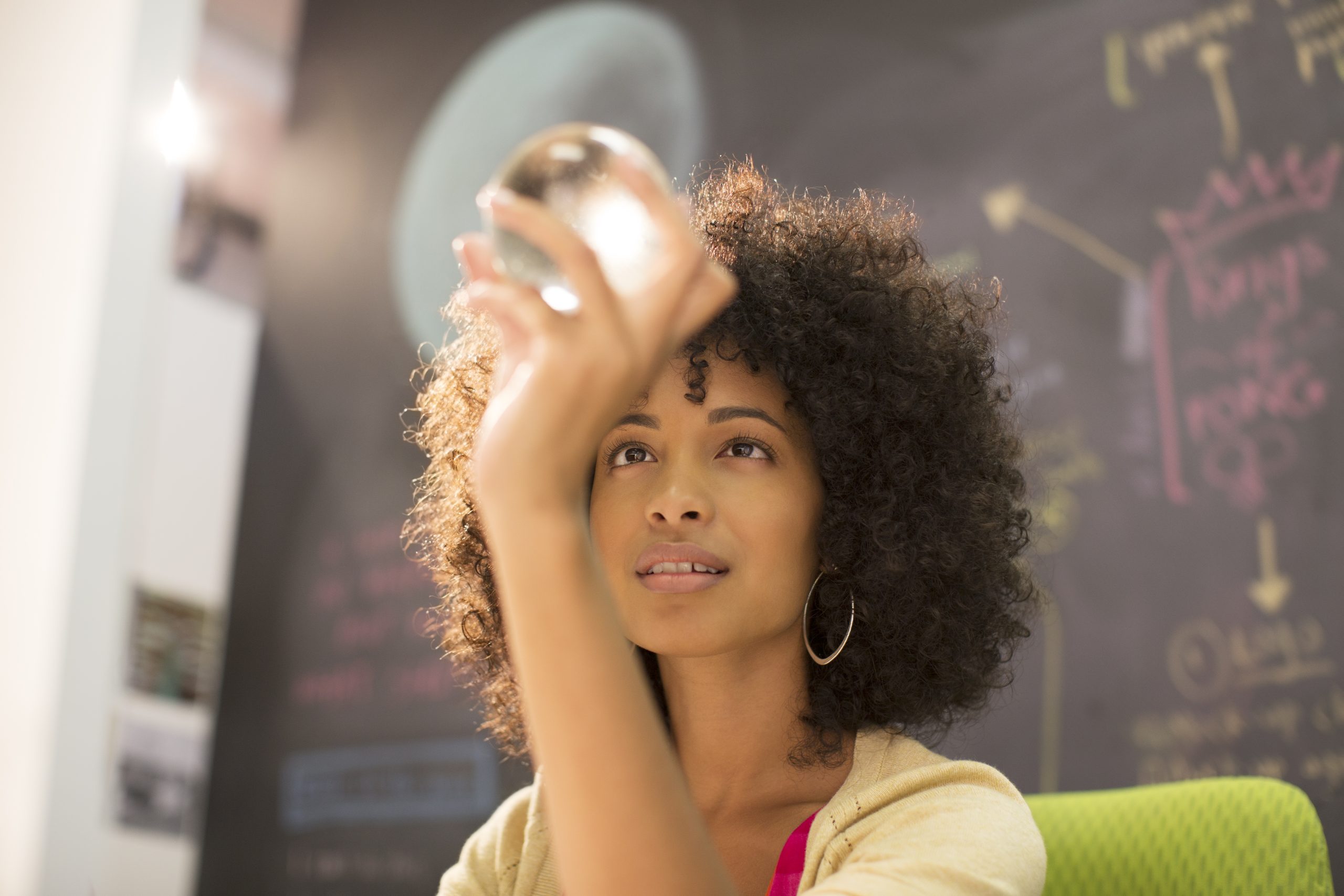 Businesswoman examining crystal ball in office