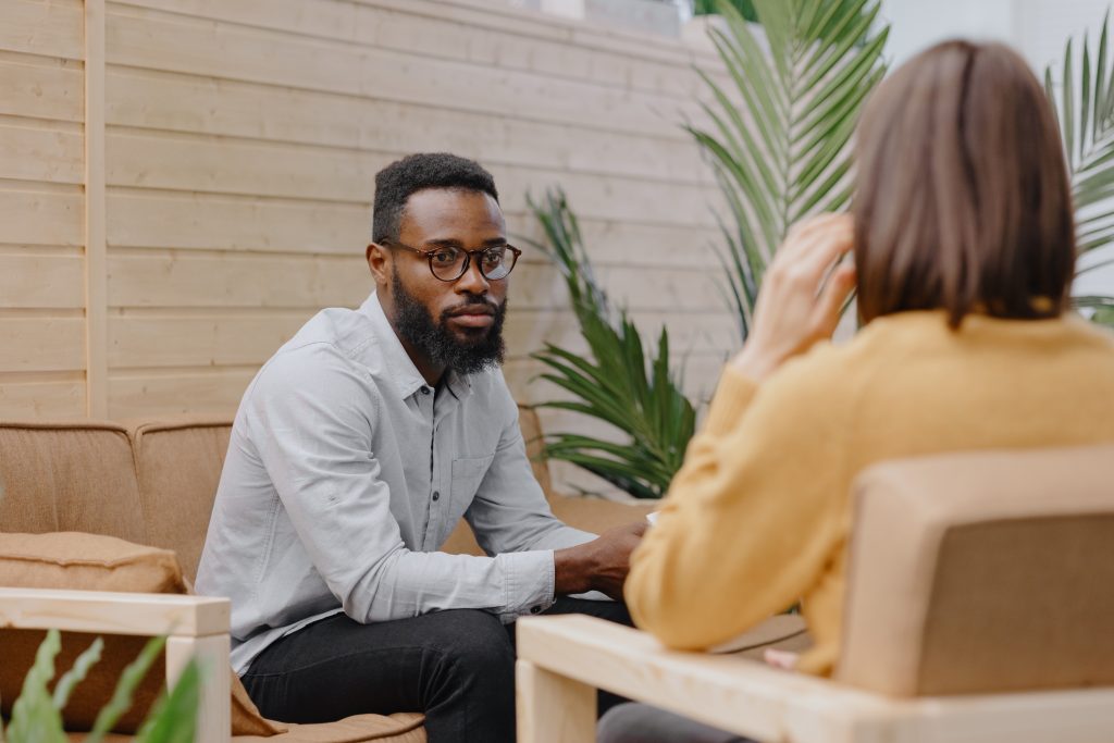 a male psychologist conducts a patient's appointment in an office or a medical center. African American male HR conducts an interview of hiring a European woman. business meeting or solving work tasks in the office or coworking