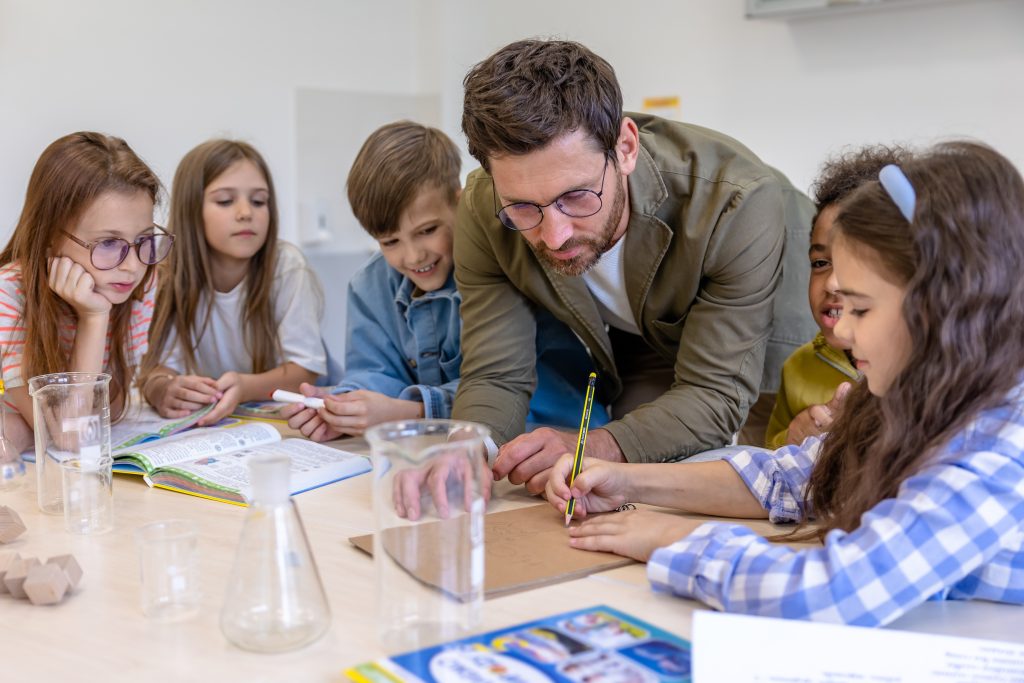 Man teacher and kids in class, learning about a new chemistry subject together.