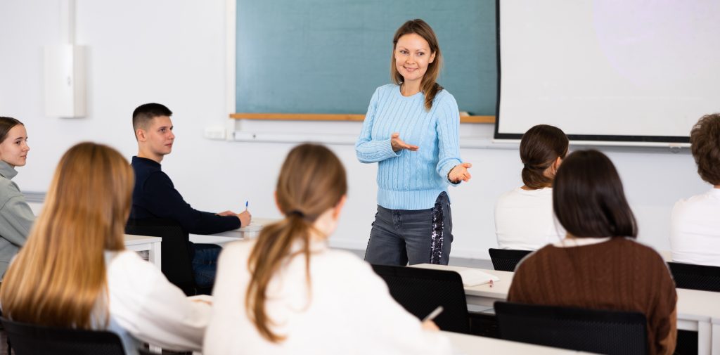 Confident young female professor talks to students in classroom